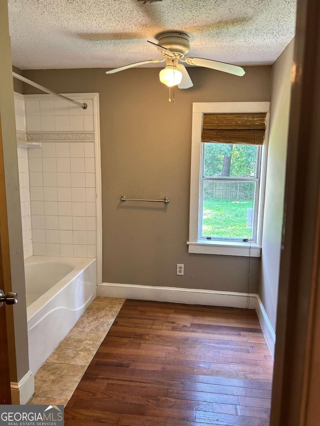 bathroom with a textured ceiling, ceiling fan, tiled shower / bath combo, and hardwood / wood-style floors