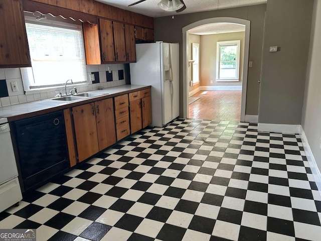 kitchen with white fridge with ice dispenser, backsplash, dishwasher, sink, and ceiling fan