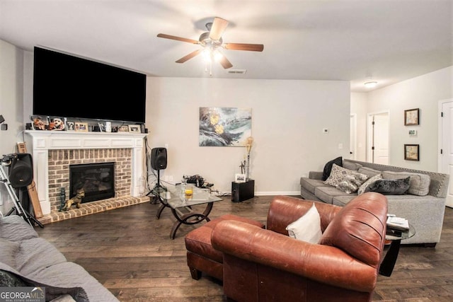 living room featuring a brick fireplace, dark wood-type flooring, and ceiling fan