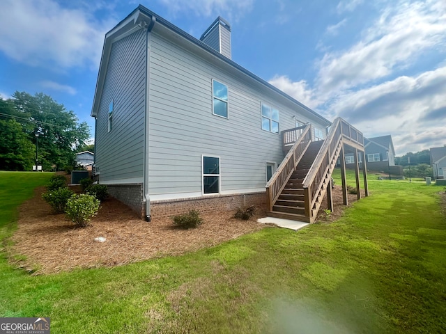 rear view of property featuring a yard and a wooden deck