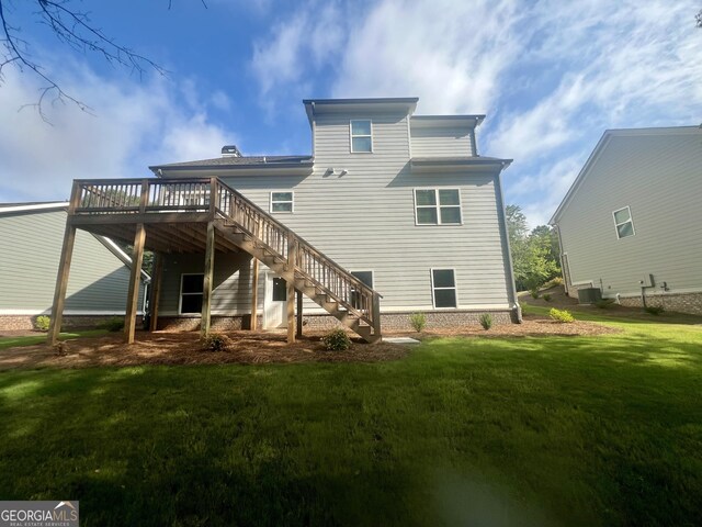 back of house with a deck and a lawn