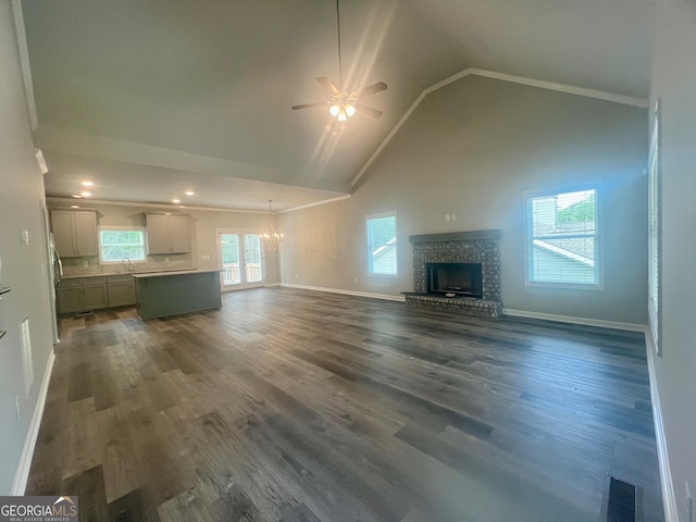 unfurnished living room with sink, a brick fireplace, hardwood / wood-style flooring, and ceiling fan with notable chandelier