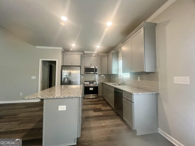 kitchen with tasteful backsplash, dark hardwood / wood-style flooring, a kitchen island, light stone countertops, and appliances with stainless steel finishes