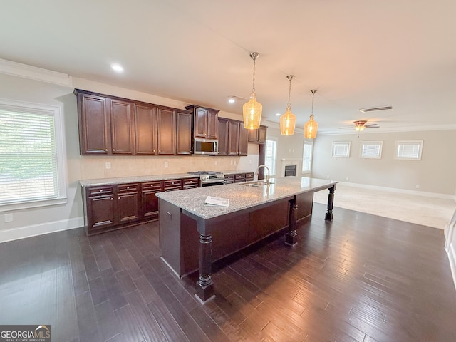 kitchen with appliances with stainless steel finishes, sink, a breakfast bar area, hanging light fixtures, and a kitchen island with sink