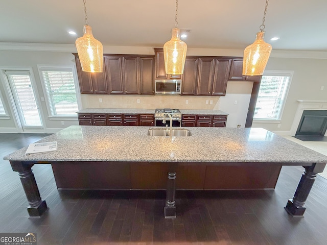 kitchen with hanging light fixtures, an island with sink, and sink