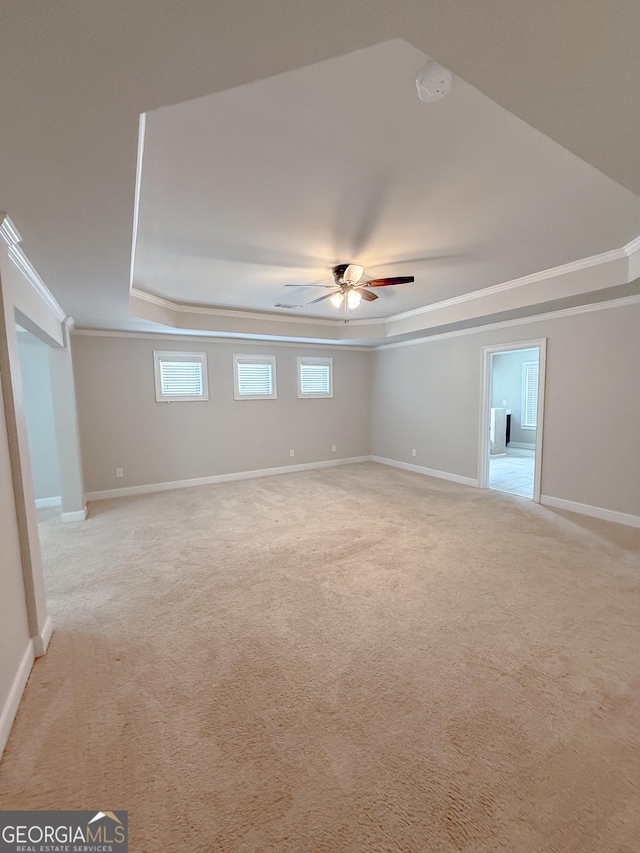 unfurnished room featuring a tray ceiling, ornamental molding, light colored carpet, and ceiling fan