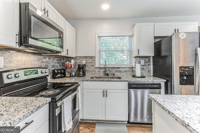 kitchen with decorative backsplash, appliances with stainless steel finishes, light wood-type flooring, and white cabinetry