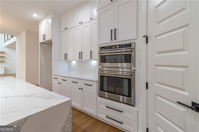 2861 Tree Top Rd, Dacula, GA 30019 - kitchen featuring stainless steel double oven, light stone counters, white cabinetry, light wood-style floors, and recessed lighting