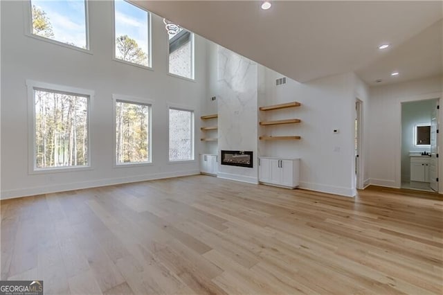 2861 Tree Top Rd, Dacula, GA 30019 - unfurnished living room with baseboards, a towering ceiling, light wood finished floors, plenty of natural light, and recessed lighting
