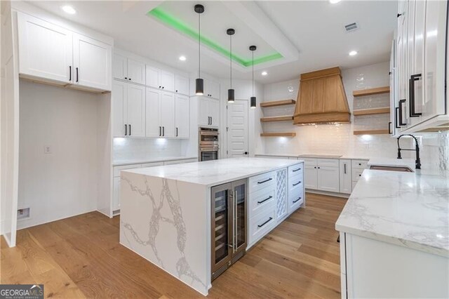 2861 Tree Top Rd, Dacula, GA 30019 - kitchen with open shelves, wine cooler, a sink, light wood-style flooring, and double oven