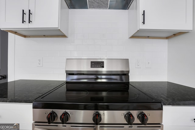 kitchen with stainless steel range, range hood, backsplash, dark stone countertops, and white cabinets