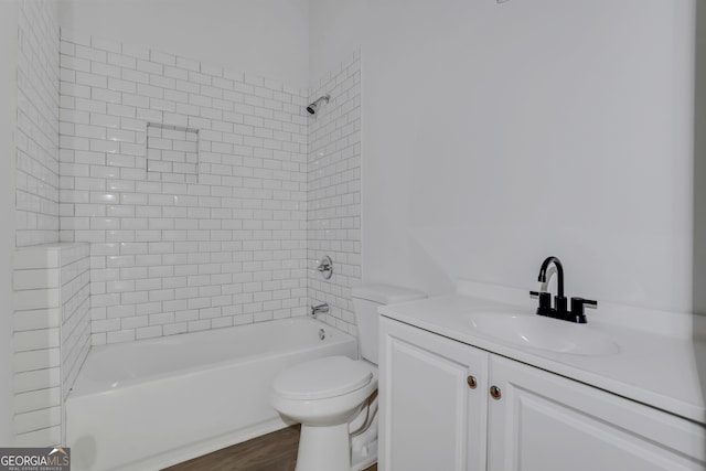 full bathroom with tiled shower / bath, vanity, hardwood / wood-style flooring, and toilet