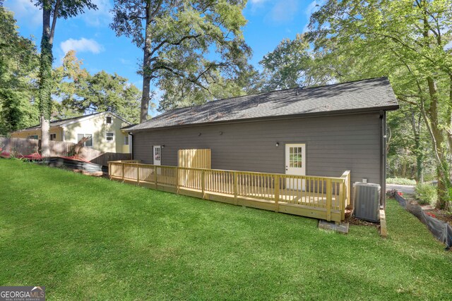 rear view of house with a wooden deck, central AC unit, and a lawn