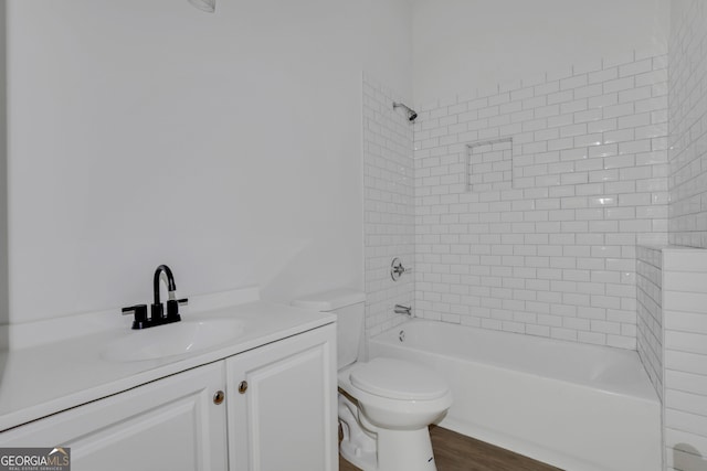 full bathroom featuring toilet, tiled shower / bath combo, vanity, and hardwood / wood-style floors