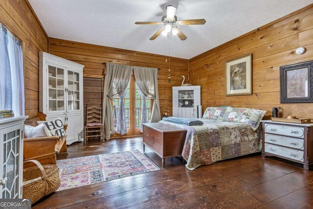 bedroom with dark wood-type flooring, ceiling fan, and wooden walls