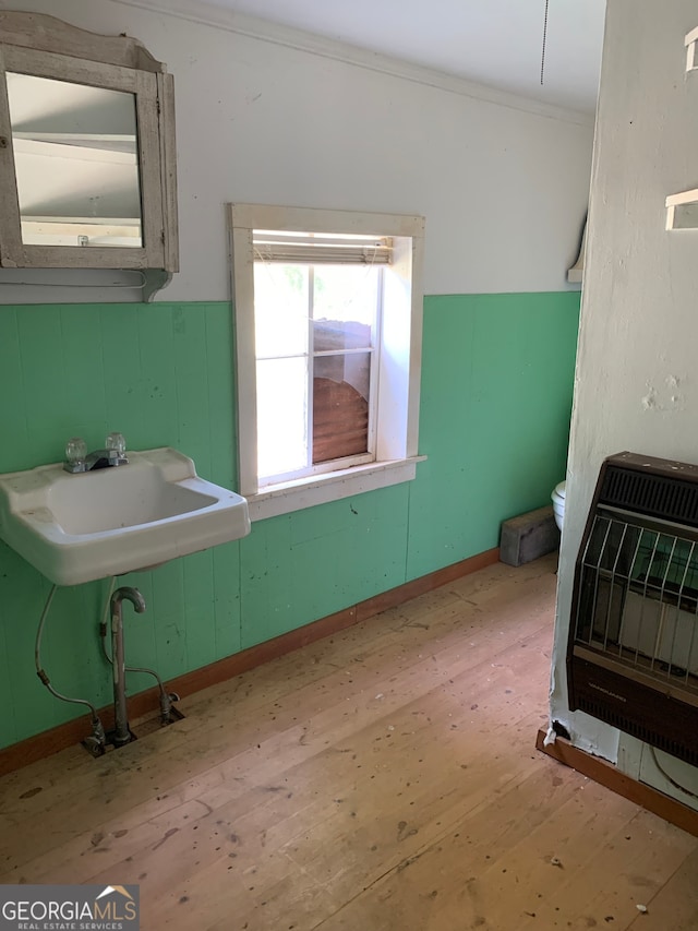 interior space featuring wood-type flooring, sink, toilet, and heating unit