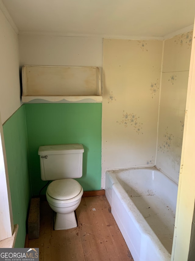 bathroom featuring hardwood / wood-style floors, a washtub, and toilet