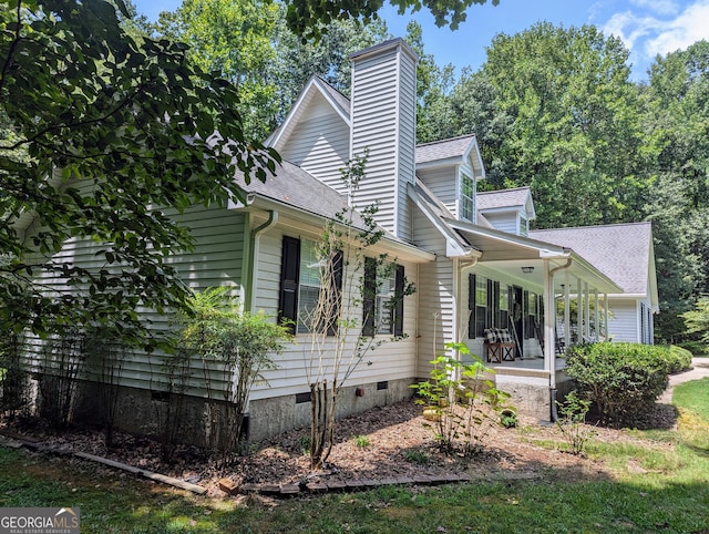 view of side of home with crawl space, covered porch, and roof with shingles