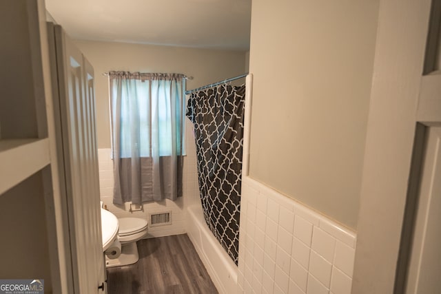 bathroom with shower / bath combo with shower curtain, tile walls, wood-type flooring, and toilet