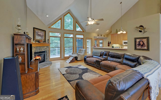 living room with high vaulted ceiling, a wealth of natural light, and a stone fireplace