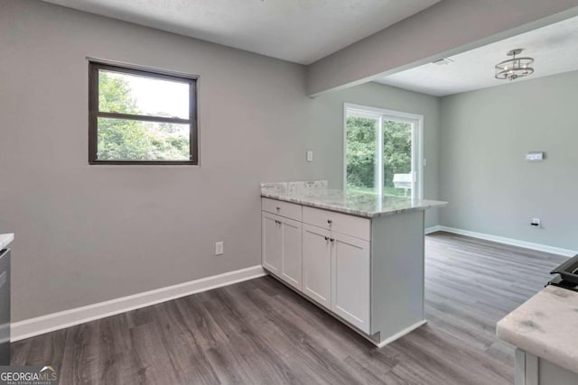 kitchen featuring white cabinetry, light stone counters, kitchen peninsula, and dark hardwood / wood-style flooring