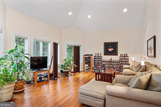 living room with high vaulted ceiling, light wood finished floors, and recessed lighting