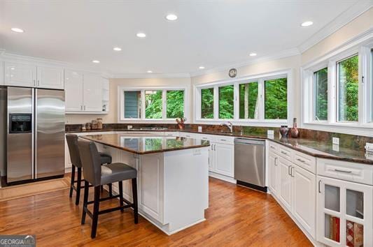 kitchen with appliances with stainless steel finishes, light hardwood / wood-style flooring, a center island, and white cabinetry