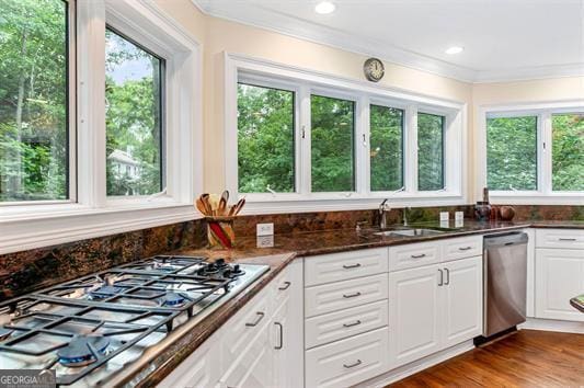 kitchen featuring appliances with stainless steel finishes, sink, dark stone countertops, white cabinetry, and hardwood / wood-style flooring