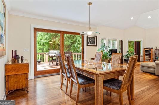 dining area featuring vaulted ceiling, light hardwood / wood-style flooring, crown molding, and plenty of natural light