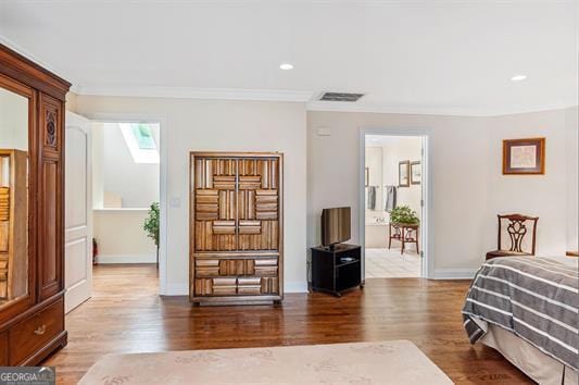 bedroom with a skylight, crown molding, and hardwood / wood-style floors