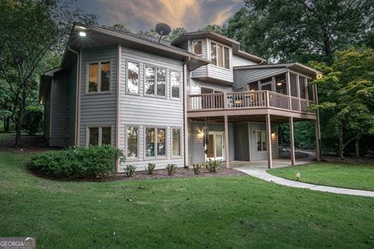 rear view of house with a sunroom, a yard, and a patio area