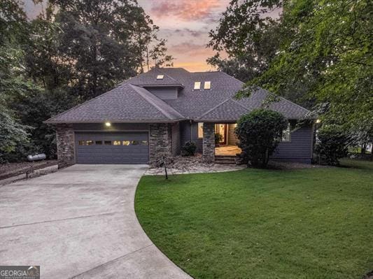 view of front facade with a lawn, a garage, concrete driveway, and roof with shingles