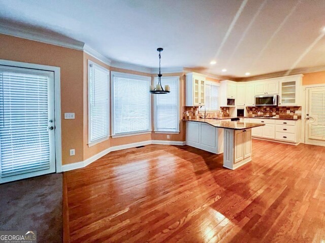 kitchen featuring decorative light fixtures, tasteful backsplash, white cabinets, sink, and light hardwood / wood-style floors