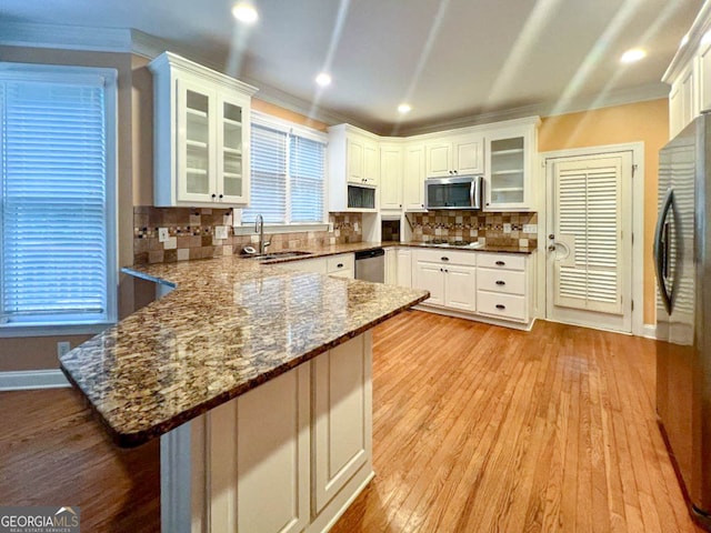 kitchen with sink, light hardwood / wood-style flooring, decorative backsplash, and stainless steel appliances