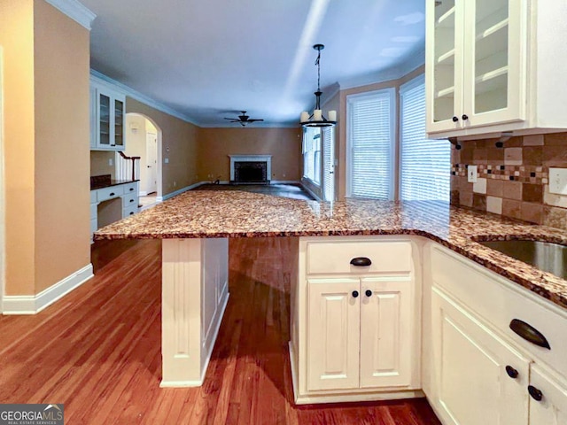 kitchen featuring ceiling fan, decorative backsplash, light stone countertops, and hardwood / wood-style flooring