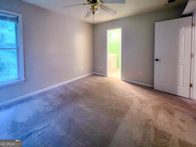 unfurnished bedroom featuring ensuite bath, ceiling fan, and carpet flooring