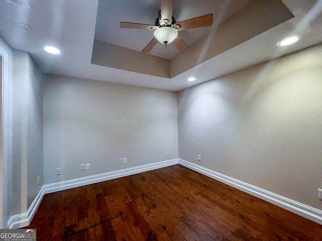 unfurnished room featuring hardwood / wood-style flooring, a tray ceiling, and ceiling fan