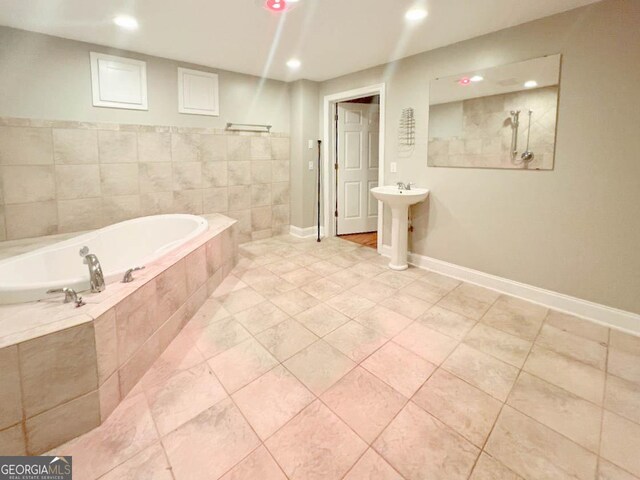 bathroom with sink, tiled tub, and tile patterned floors