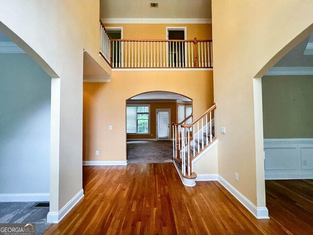 foyer entrance with hardwood / wood-style flooring, ornamental molding, and a high ceiling