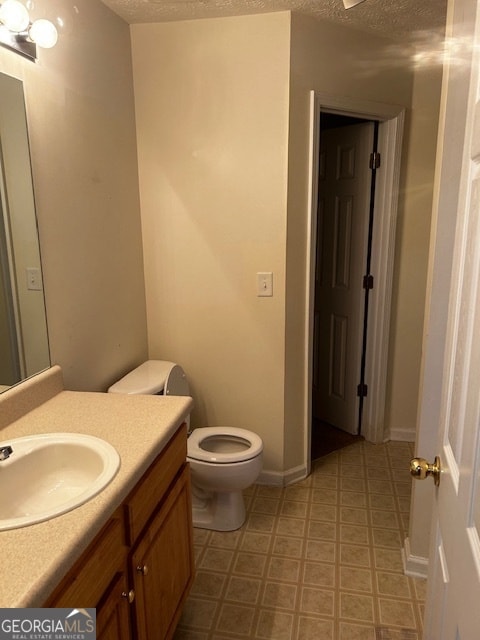 bathroom with tile patterned floors, toilet, vanity, and a textured ceiling