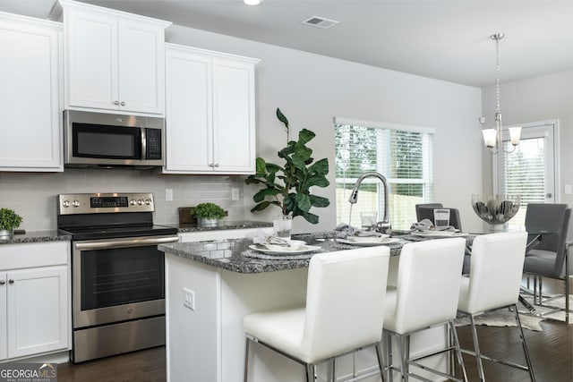 kitchen featuring an island with sink, stainless steel appliances, white cabinetry, and a breakfast bar