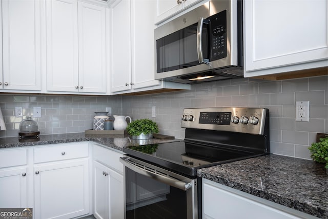 kitchen with dark stone countertops, white cabinets, appliances with stainless steel finishes, and decorative backsplash