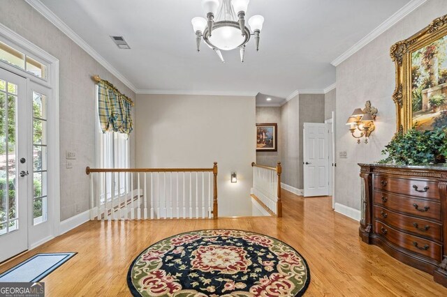 entrance foyer with an inviting chandelier, wood-type flooring, and crown molding