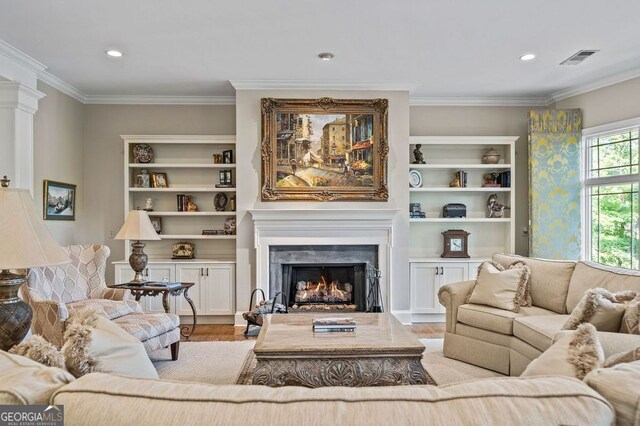 living room with built in features, light hardwood / wood-style floors, crown molding, and a premium fireplace