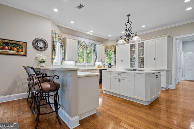 kitchen featuring white cabinetry, light hardwood / wood-style floors, and decorative light fixtures