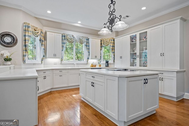 kitchen with hanging light fixtures, light hardwood / wood-style flooring, white cabinetry, and crown molding