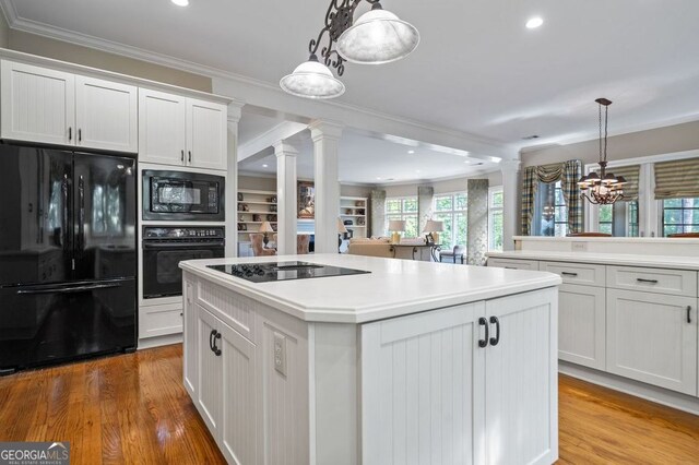 kitchen featuring hardwood / wood-style flooring, black appliances, crown molding, and hanging light fixtures