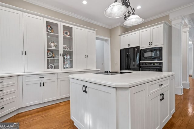 kitchen with white cabinetry, black appliances, pendant lighting, a center island, and light hardwood / wood-style floors