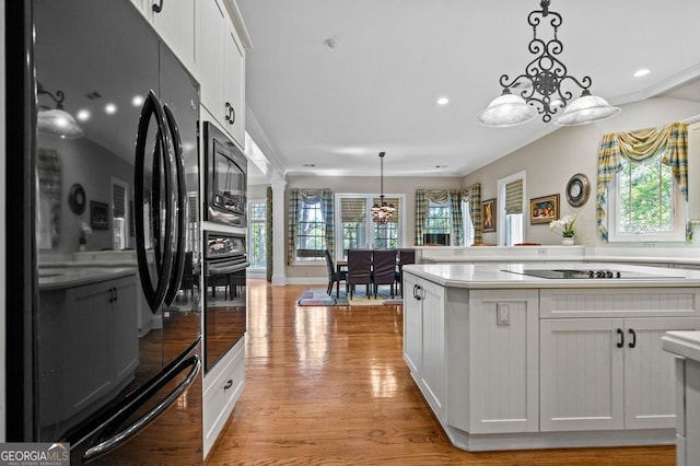 kitchen featuring light hardwood / wood-style floors, black appliances, a healthy amount of sunlight, and pendant lighting