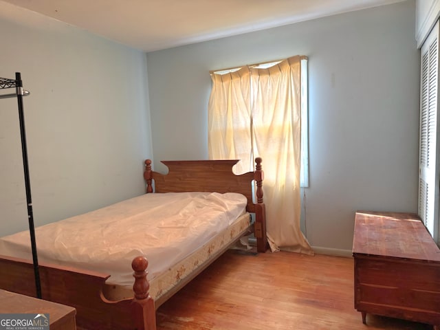 bedroom featuring multiple windows, light wood-type flooring, and a closet